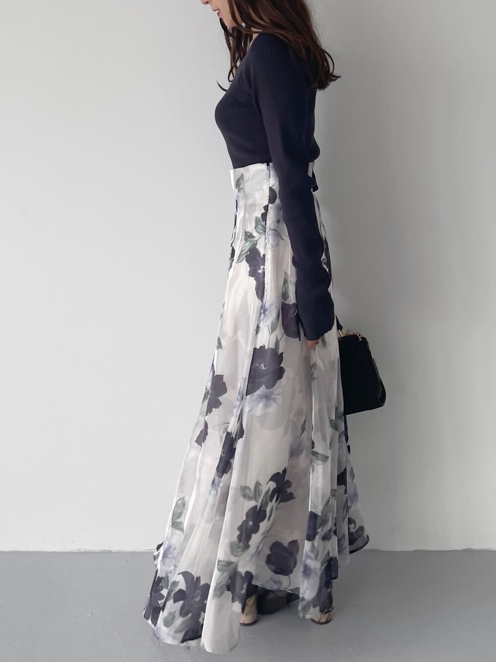 ブルー系のスカート、ブラウン系のブーツ、ブラック系のショルダーバッグを着用したレディースの秋コーディネートの4枚目の写真