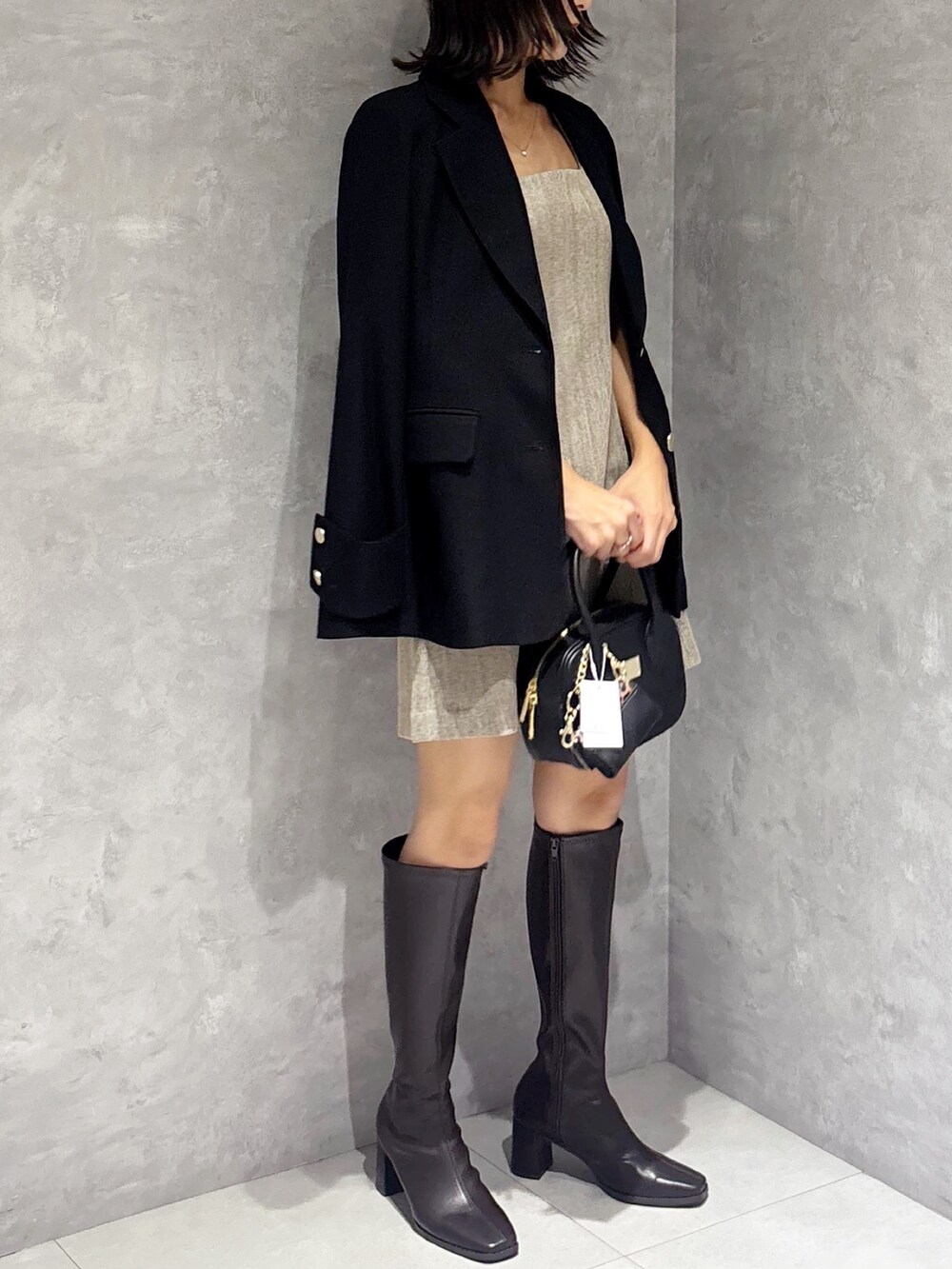 ブラウン系のワンピース、ブラウン系のブーツ、ブラック系のハンドバッグを着用したレディースの秋コーディネートの5枚目の写真