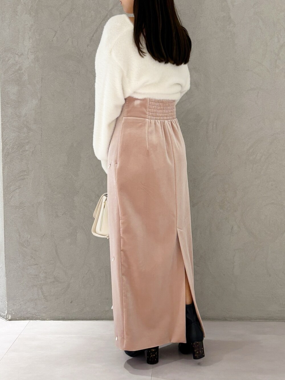 ピンク系のスカート、ブラック系のブーツ、ホワイト系のニット/セーターを着用したレディースの冬コーディネートの5枚目の写真