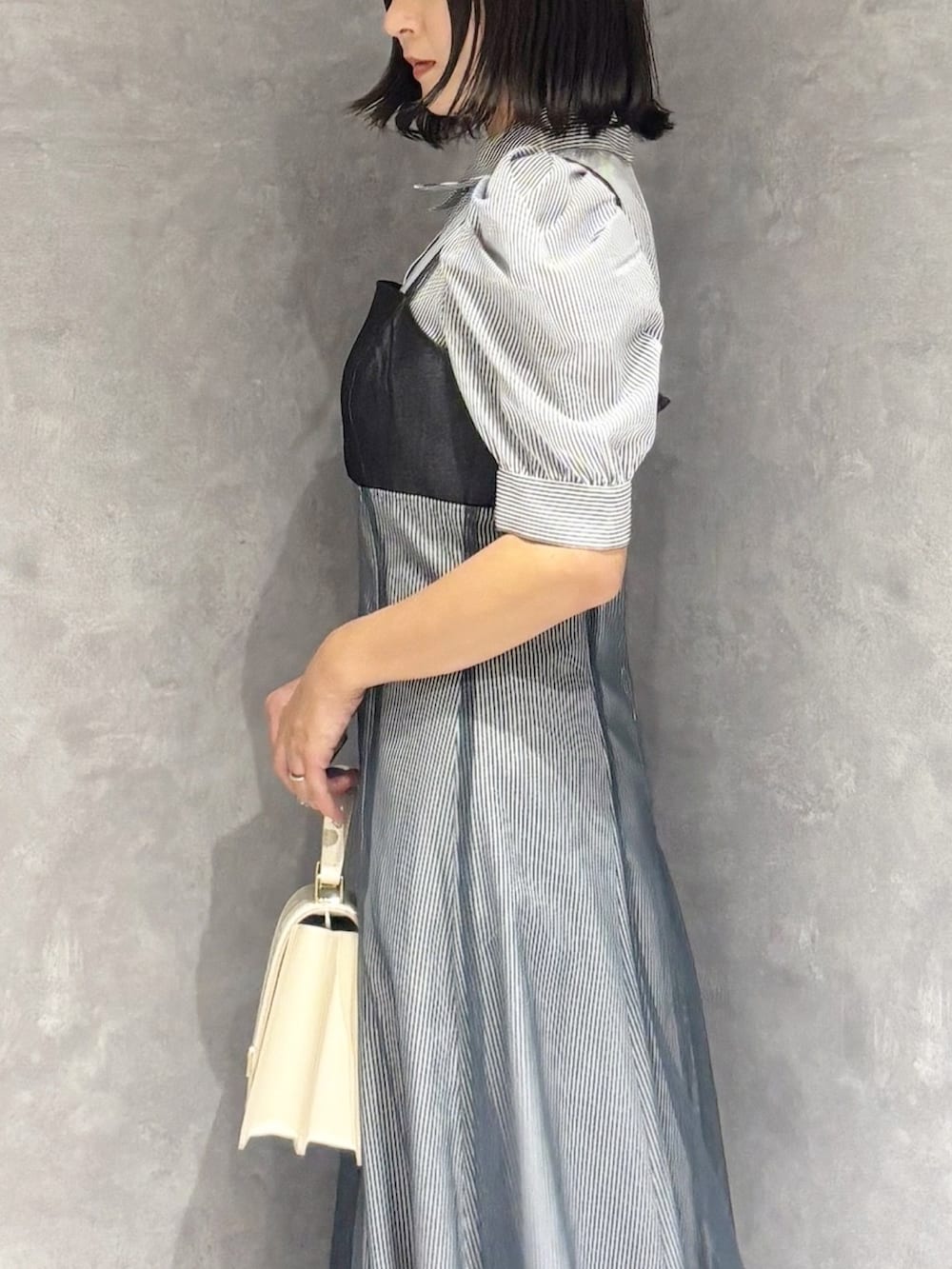 ブラック系のパンプス、ホワイト系のハンドバッグ、ブルー系のワンピースを着用したレディースの秋コーディネートの4枚目の写真