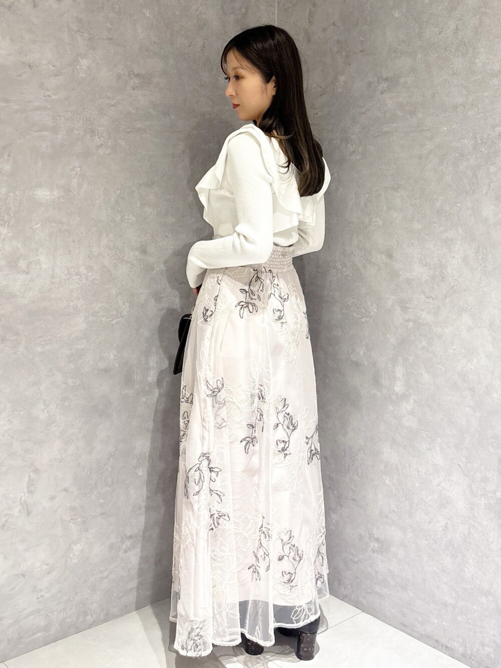 ブラウン系のハンドバッグ、ブラック系のブーツ、ベージュ系のスカートを着用したレディースの冬コーディネートの3枚目の写真