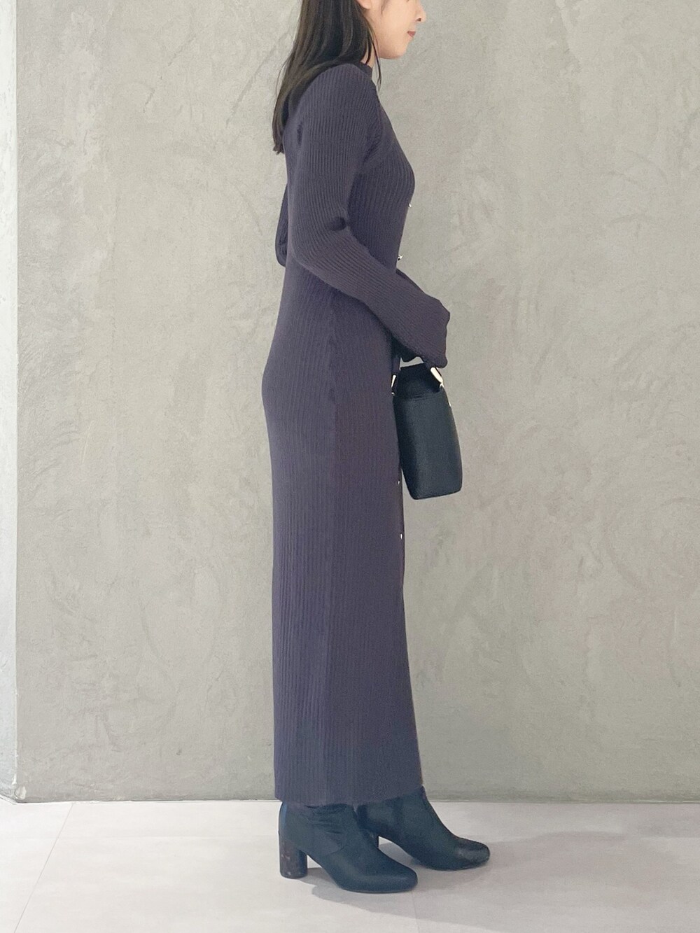 ブラック系のハンドバッグ、ブラック系のブーツ、グレー系のワンピースを着用したレディースの冬コーディネートの3枚目の写真