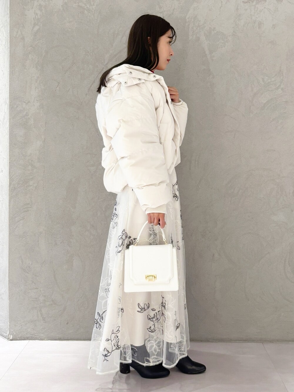 ホワイト系のスカート、ブラック系のブーツ、ホワイト系のハンドバッグを着用したレディースの冬コーディネートの3枚目の写真