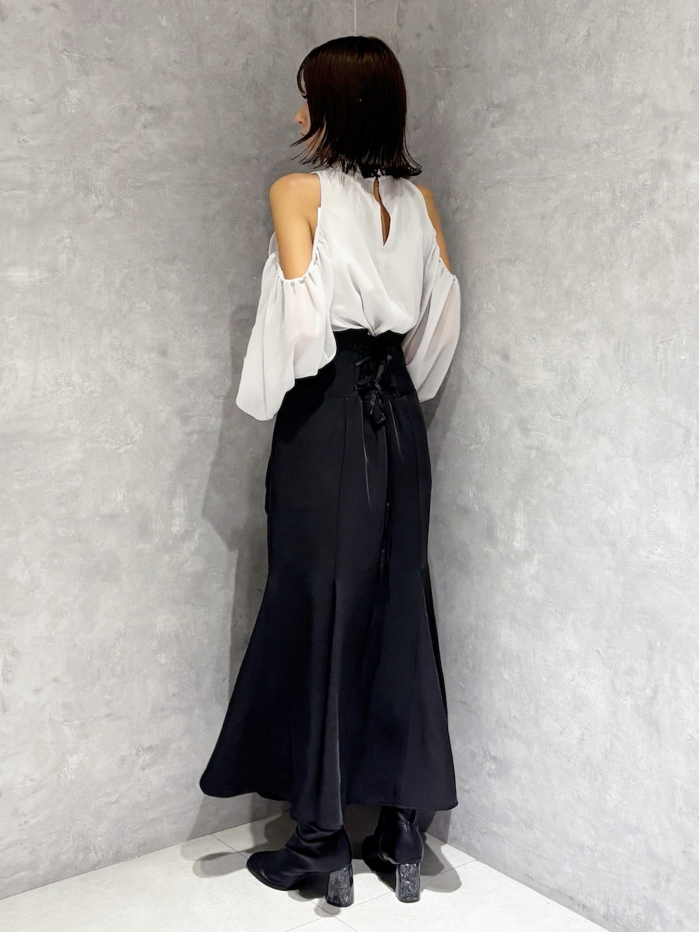 ブラック系のハンドバッグ、ブラック系のブーツ、ブラック系のスカートを着用したレディースの秋コーディネートの3枚目の写真