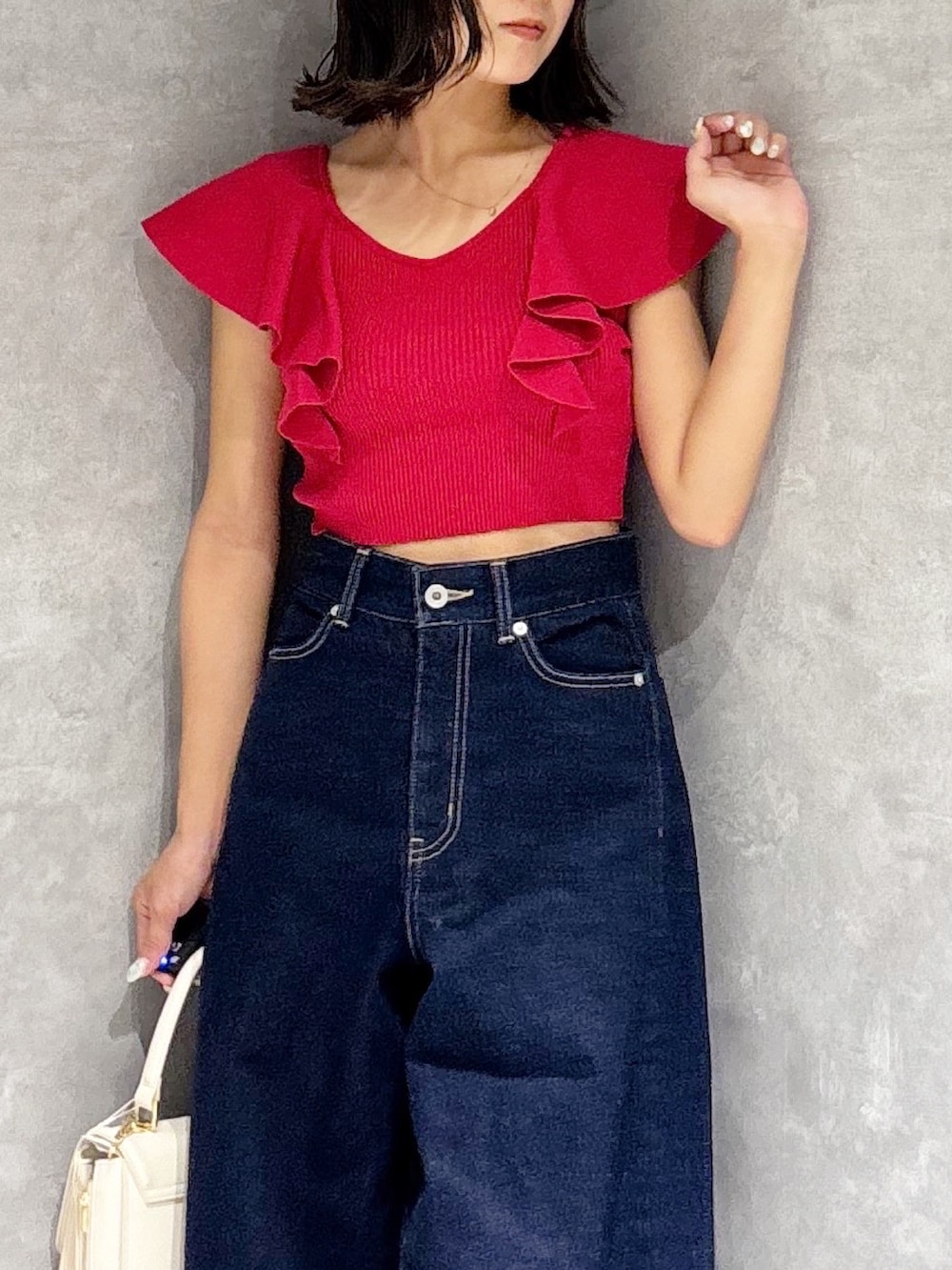 ブルー系のデニムパンツ、ブラウン系のサンダル、ホワイト系のハンドバッグを着用したレディースの夏コーディネートの5枚目の写真