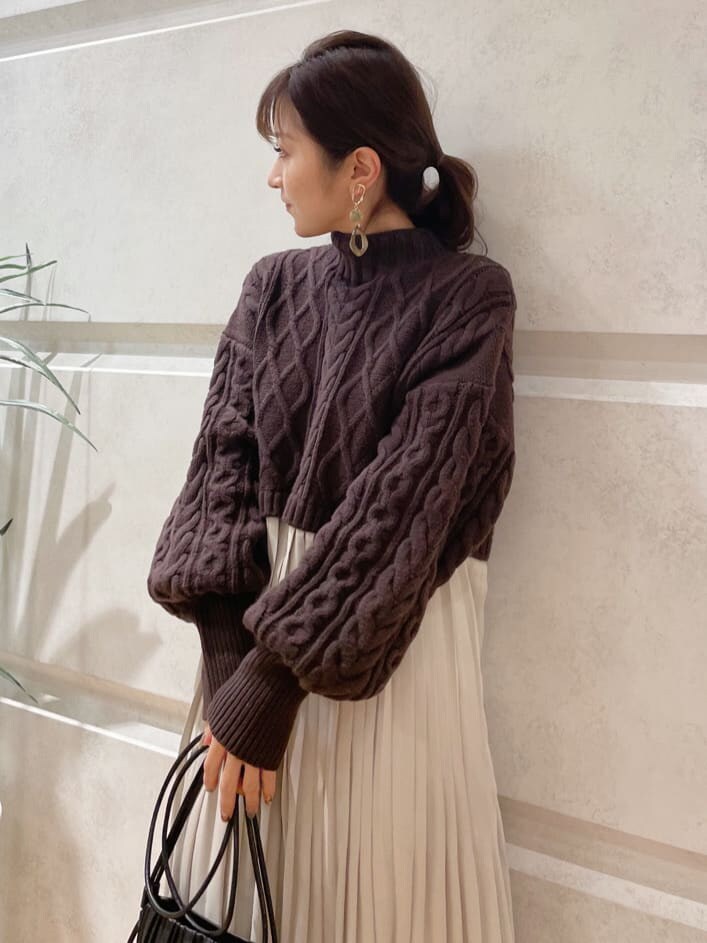 ベージュ系のショルダーバッグ、ブラウン系のワンピース、ゴールド系のピアス（両耳用）を着用したレディースの冬コーディネートの2枚目の写真