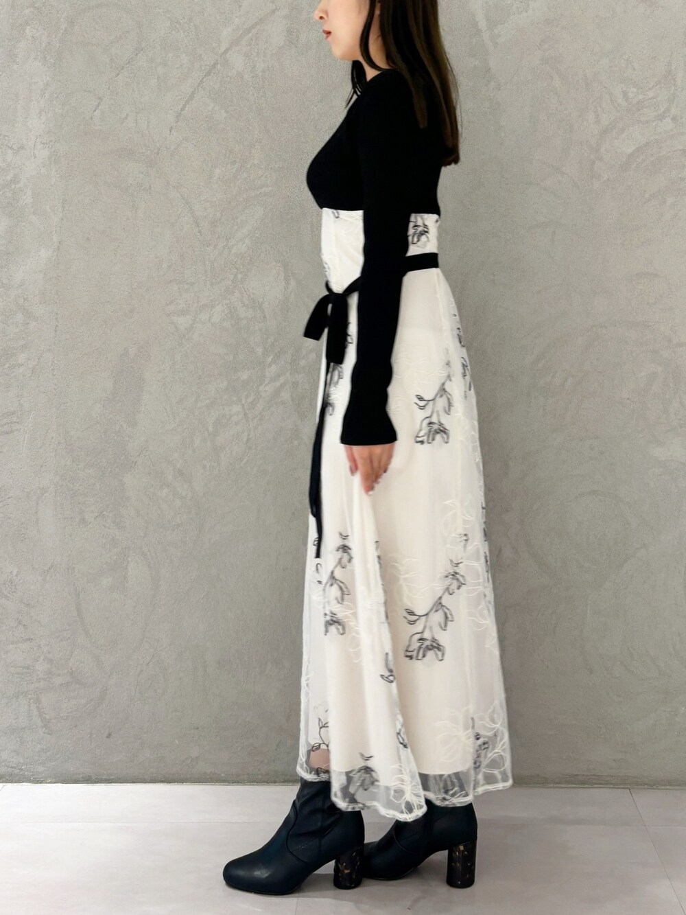 ホワイト系のワンピース、ブラック系のブーツ、ホワイト系のハンドバッグを着用したレディースの秋コーディネートの2枚目の写真