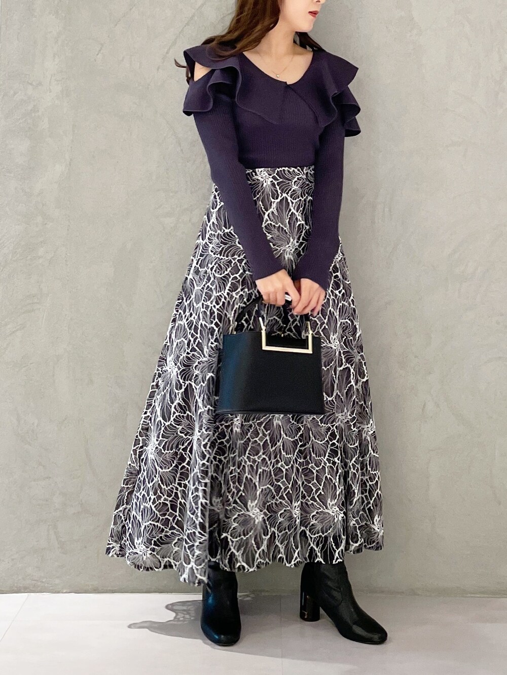 グレー系のスカート、ブラック系のブーツ、ブラック系のハンドバッグを着用したレディースの冬コーディネートの2枚目の写真