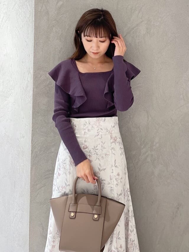 ピンク系のスカート、ブラウン系のハンドバッグ、パープル系のニット/セーターを着用したレディースの秋コーディネートの2枚目の写真