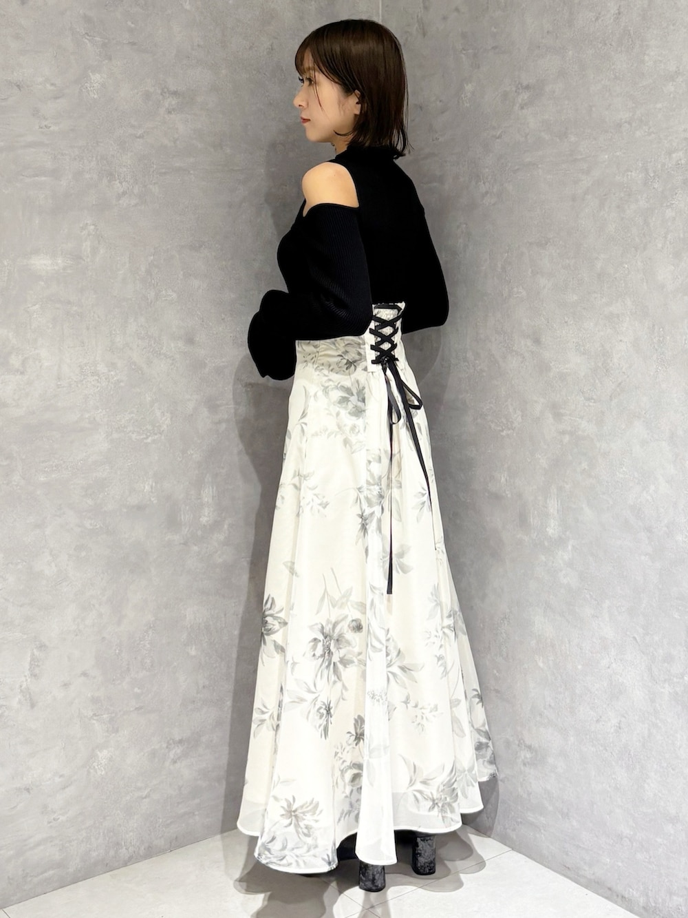 ホワイト系のスカート、ブラック系のニット/セーター、ブラック系のブーツを着用したレディースの冬コーディネートの4枚目の写真