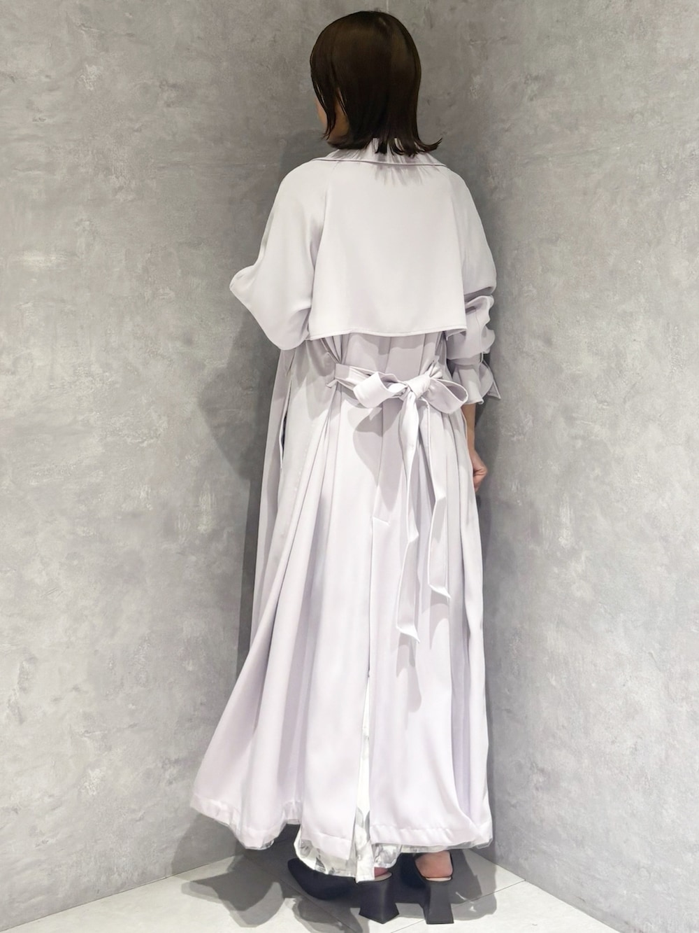 ブラック系のワンピース、ブラウン系のパンプス、パープル系のトレンチコートを着用したレディースの春コーディネートの2枚目の写真