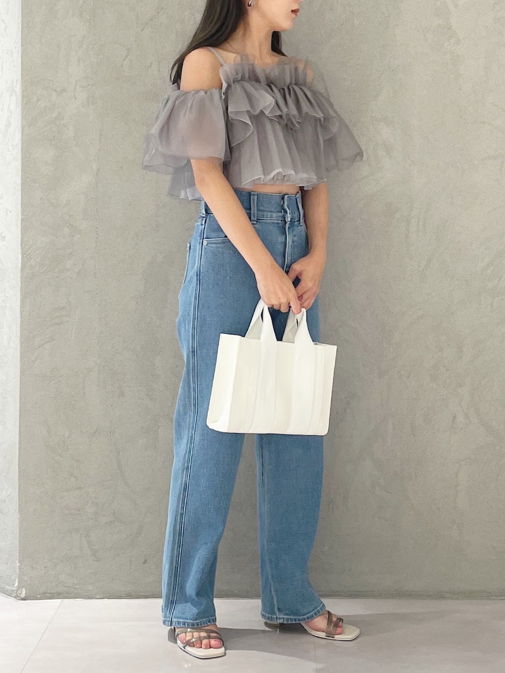 ブルー系のデニムパンツ、ホワイト系のサンダル、ホワイト系のトートバッグを着用したレディースの夏コーディネートの2枚目の写真
