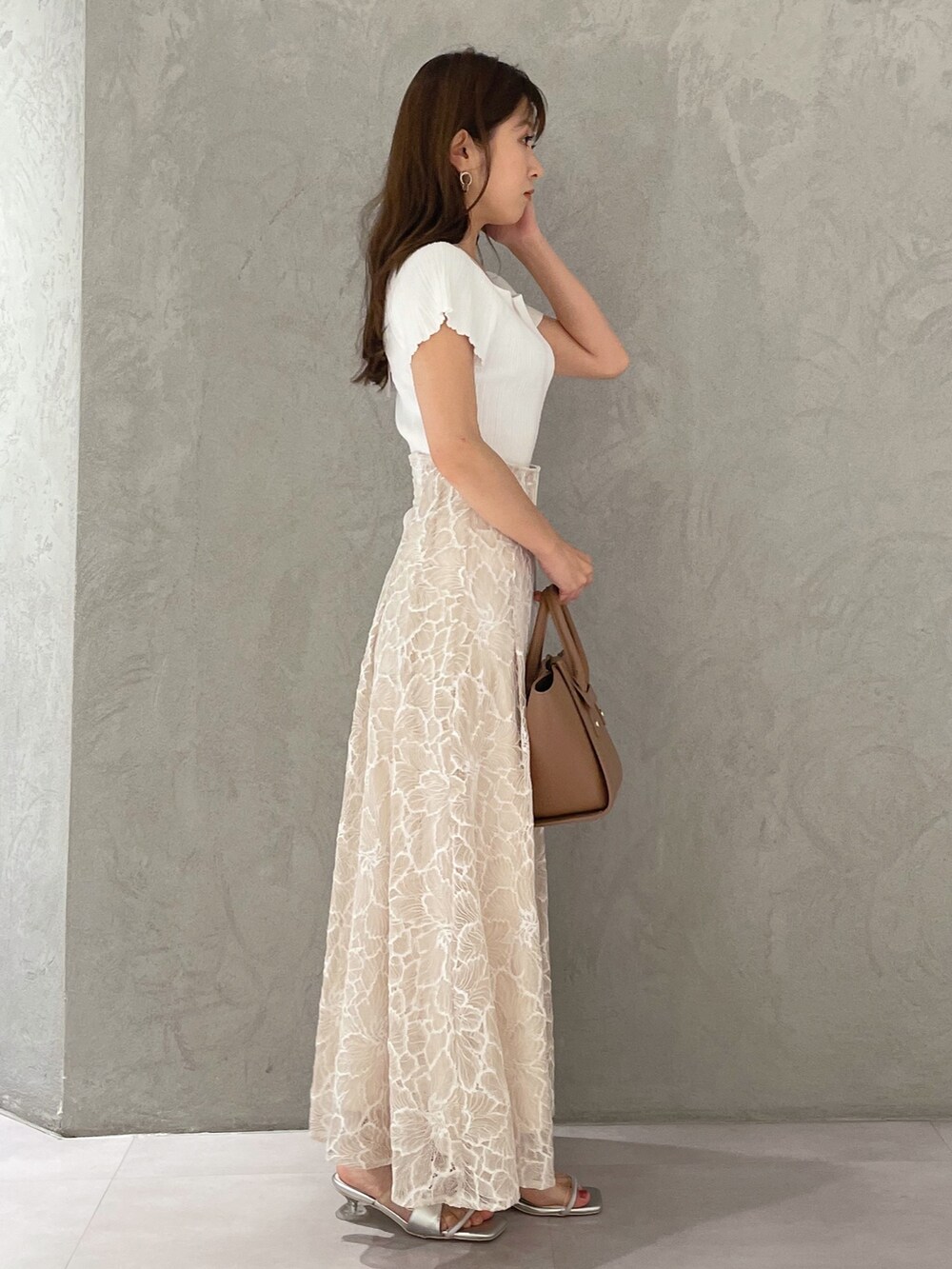 ブラウン系のトートバッグ、ホワイト系のニット/セーター、ベージュ系のスカートを着用したレディースの夏コーディネートの6枚目の写真