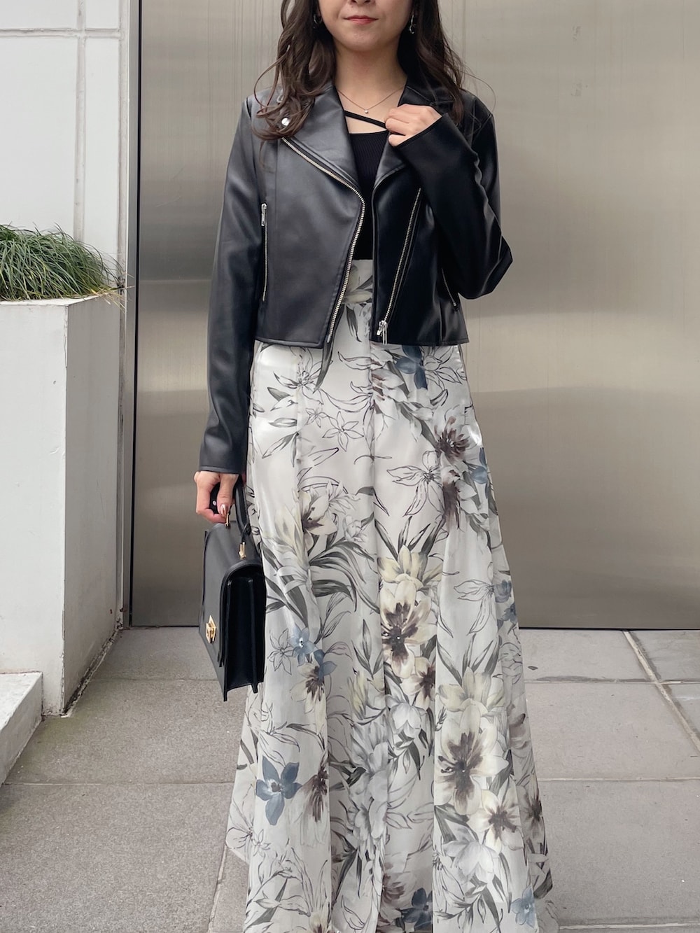 グリーン系のスカート、ブラック系のライダースジャケット、ブラック系のニット/セーターを着用したレディースの冬コーディネートの2枚目の写真