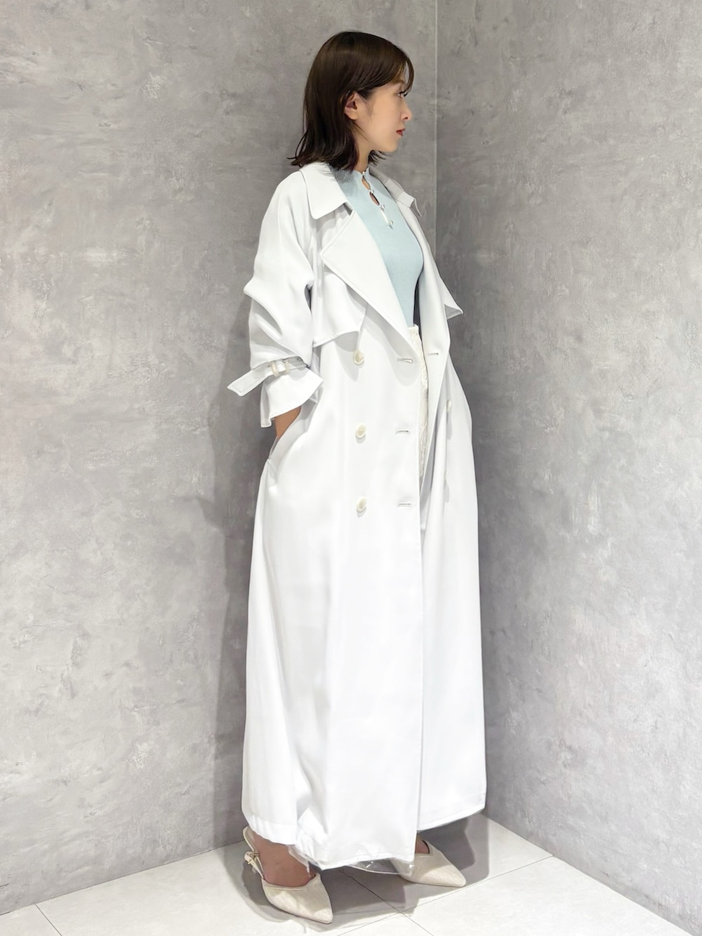 ホワイト系のスカート、ブルー系のトレンチコート、グリーン系のニット/セーターを着用したレディースの春コーディネートの2枚目の写真