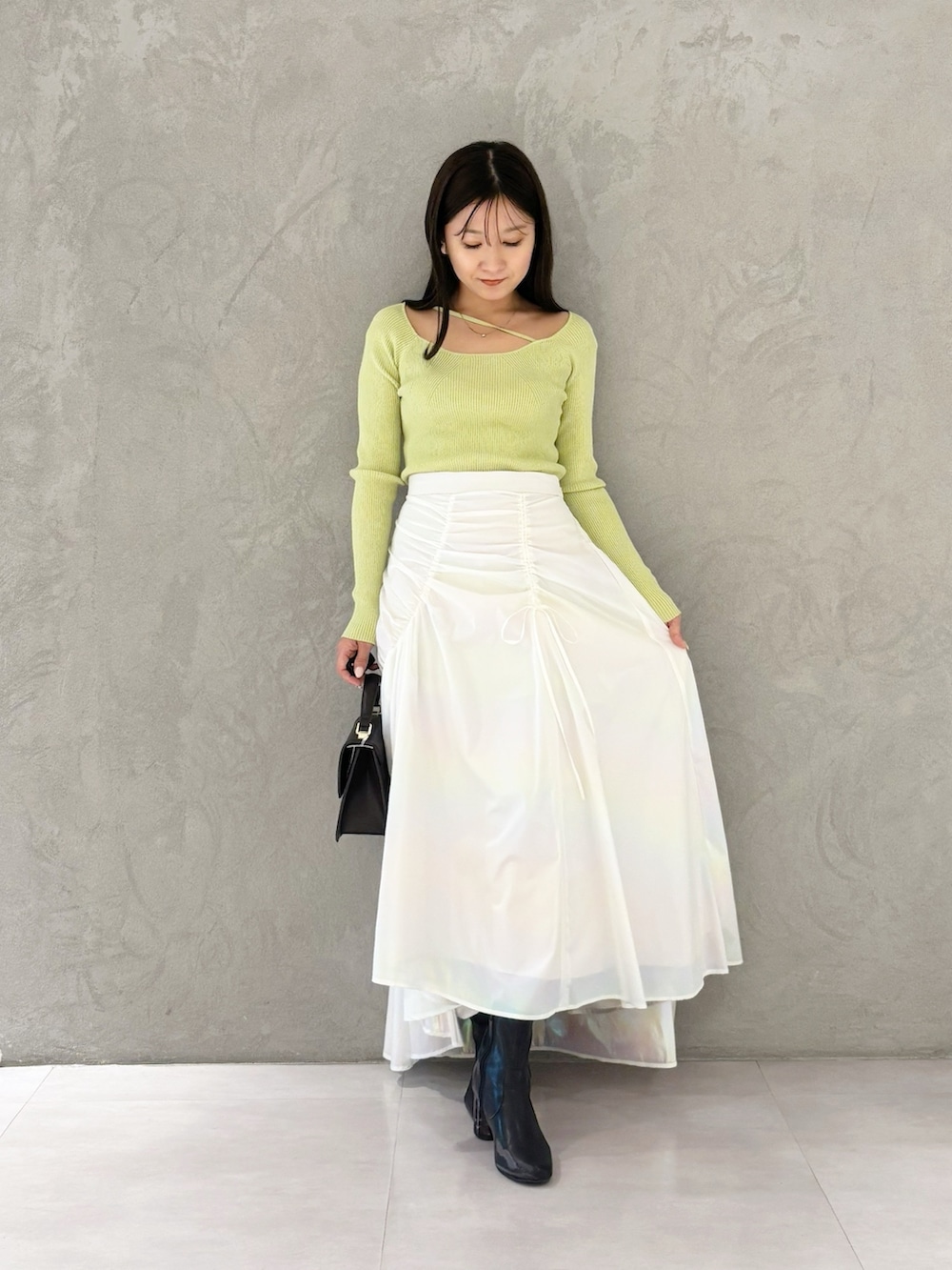 ホワイト系のスカート、ブラック系のブーツ、ブラウン系のハンドバッグを着用したレディースの冬コーディネートの7枚目の写真