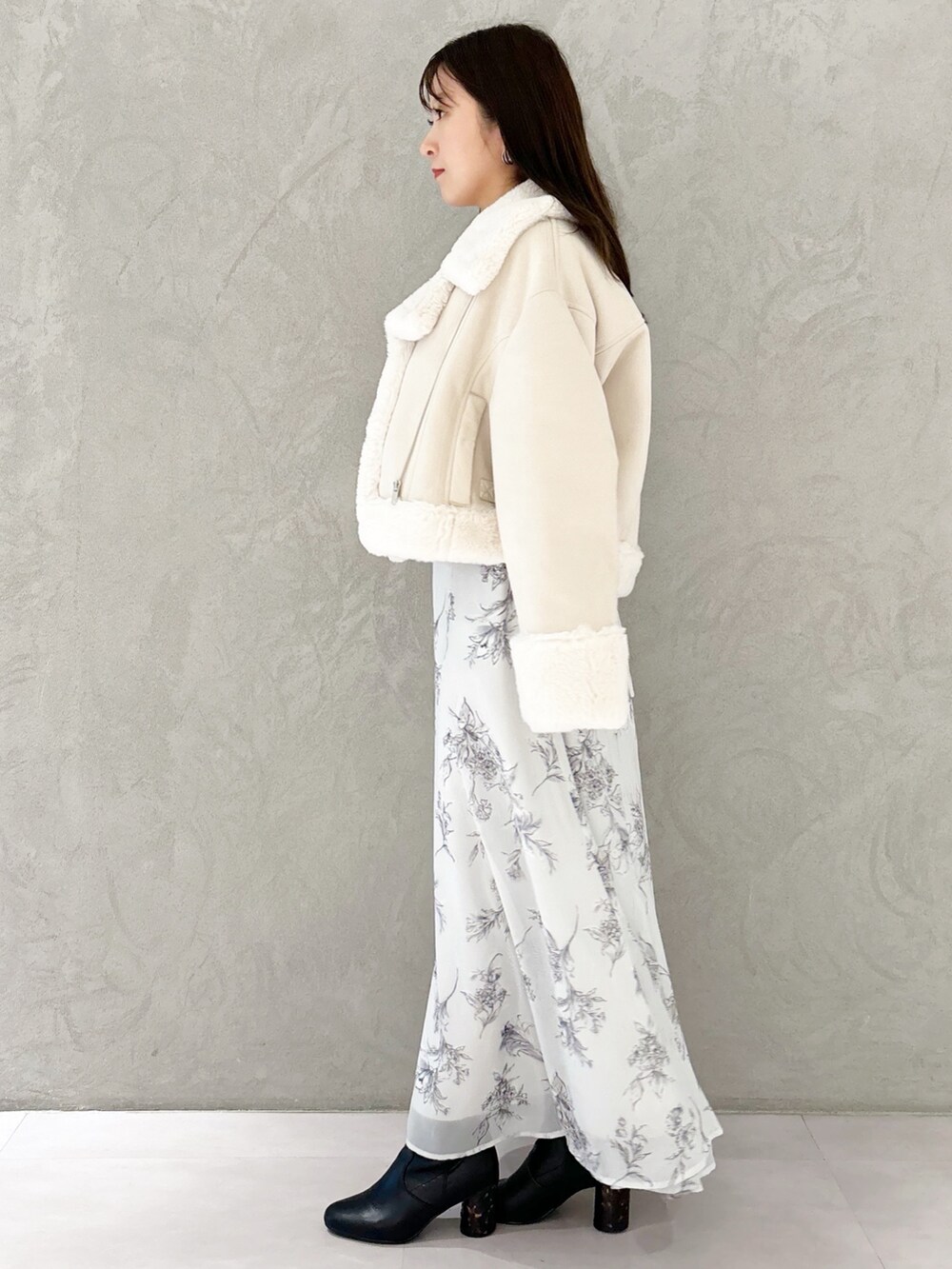 ブラック系のワンピース、ブラック系のブーツ、ホワイト系のハンドバッグを着用したレディースの秋コーディネートの6枚目の写真