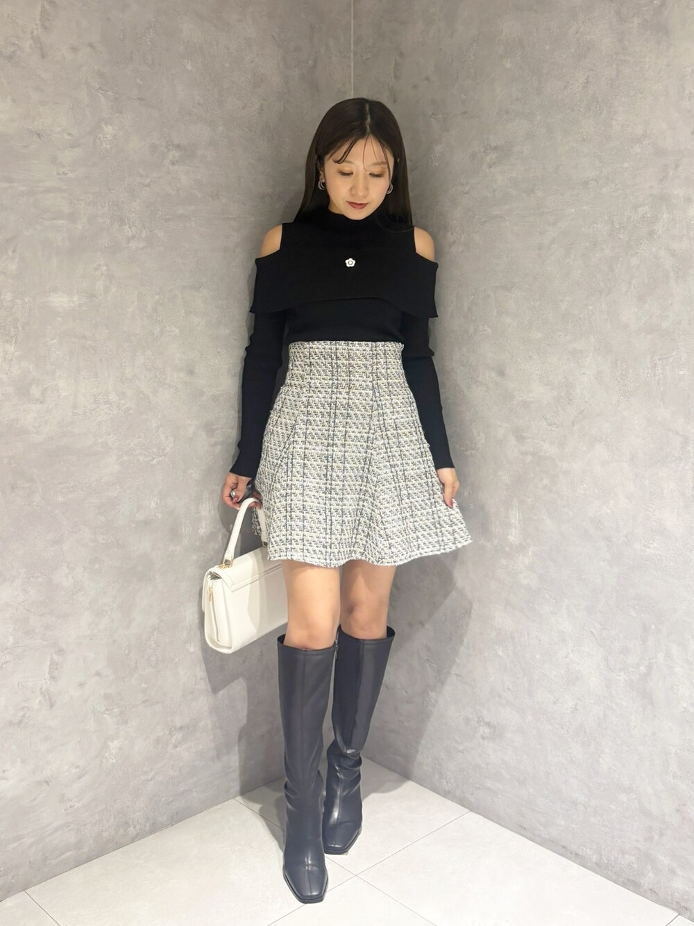 ブラック系のブーツ、ホワイト系のハンドバッグ、ブラック系のニット/セーターを着用したレディースの冬コーディネートの6枚目の写真