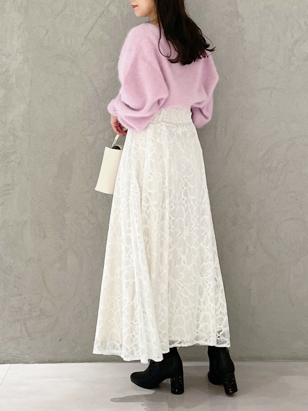 ホワイト系のハンドバッグ、ブラック系のブーツ、ホワイト系のスカートを着用したレディースの秋コーディネートの2枚目の写真