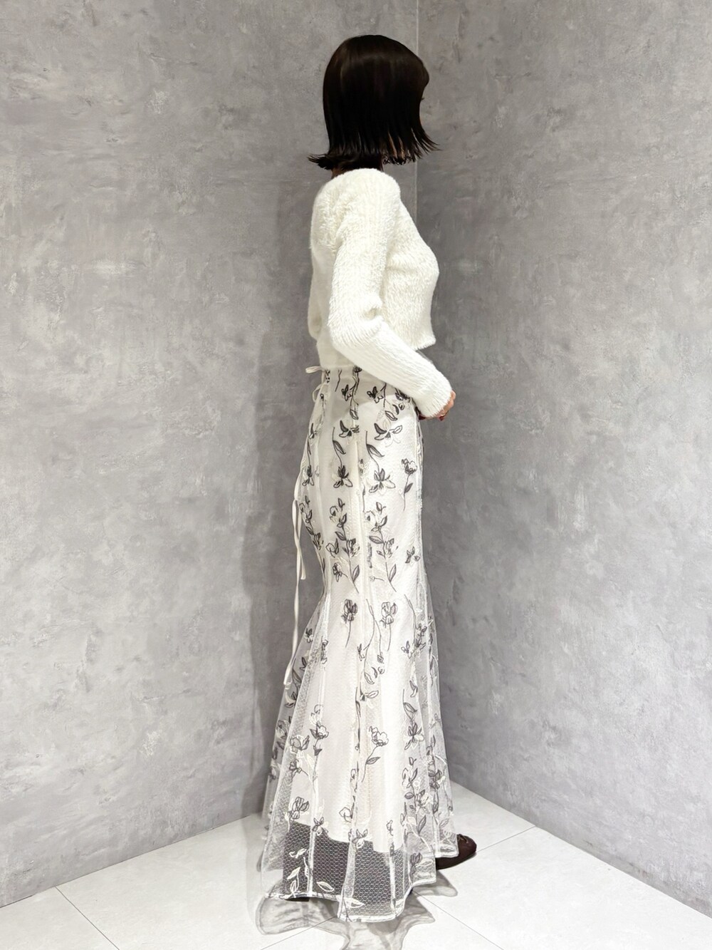 ホワイト系のスカート、ブラウン系のブーツ、ホワイト系のニット/セーターを着用したレディースの秋コーディネートの2枚目の写真