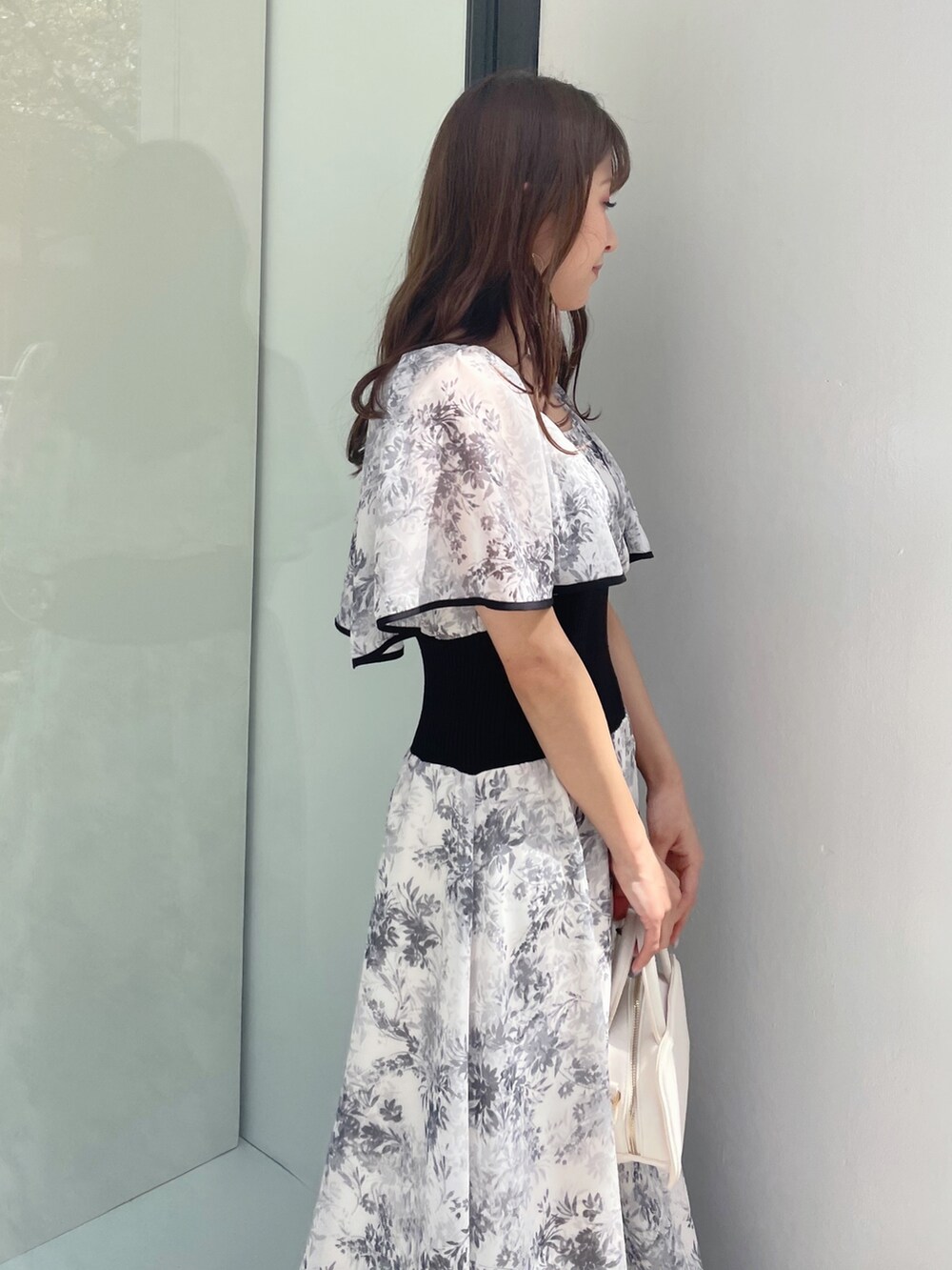 ブラック系のサンダル、ホワイト系のハンドバッグ、ホワイト系のワンピースを着用したレディースの春コーディネートの6枚目の写真