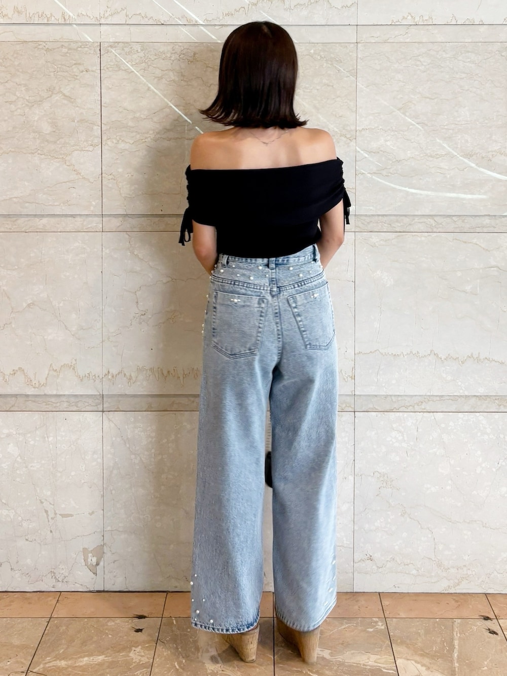 ブラック系のボディバッグ/ウエストポーチ、ブラック系のニット/セーター、ブルー系のデニムパンツを着用したレディースの夏コーディネートの3枚目の写真