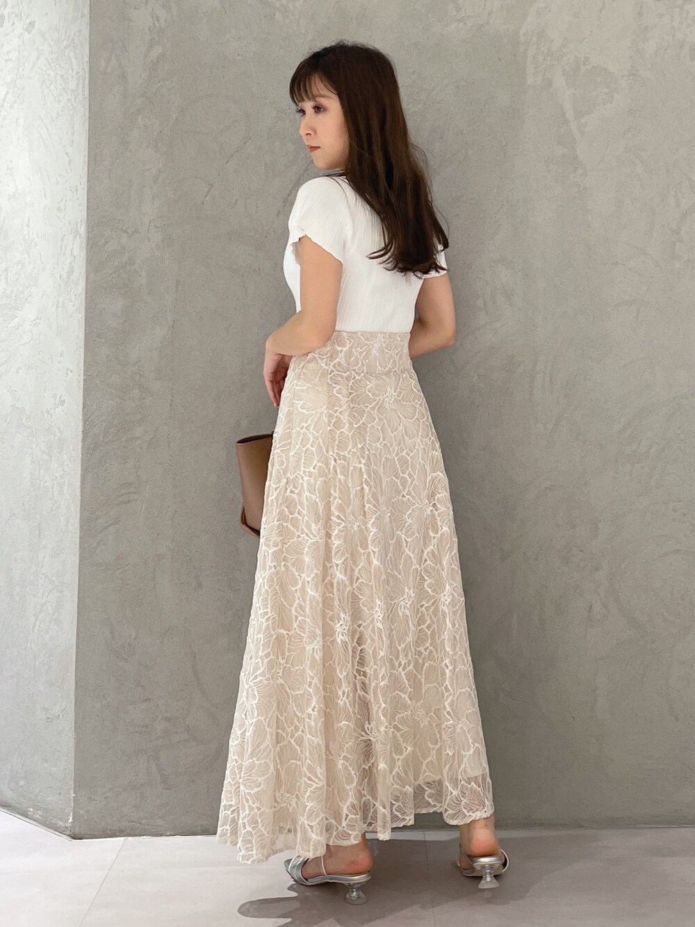 ブラウン系のトートバッグ、ホワイト系のニット/セーター、ベージュ系のスカートを着用したレディースの夏コーディネートの3枚目の写真