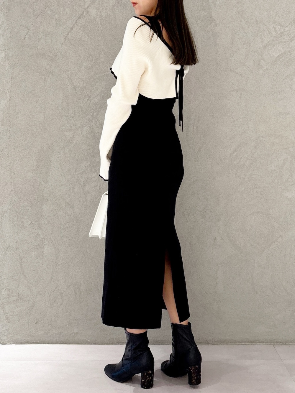 ブラック系のブーツ、ホワイト系のハンドバッグ、ブラック系のワンピースを着用したレディースの冬コーディネートの3枚目の写真