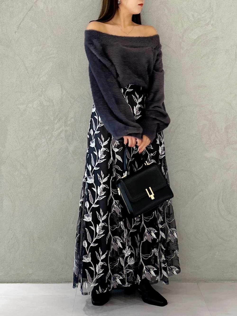 グレー系のスカート、ブラック系のブーツ、ブラック系のショルダーバッグを着用したレディースの秋コーディネートの6枚目の写真