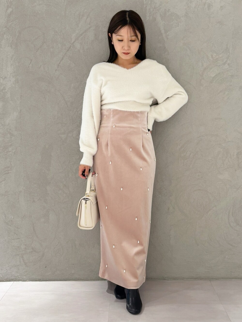 ピンク系のスカート、ブラック系のブーツ、ホワイト系のニット/セーターを着用したレディースの冬コーディネートの6枚目の写真