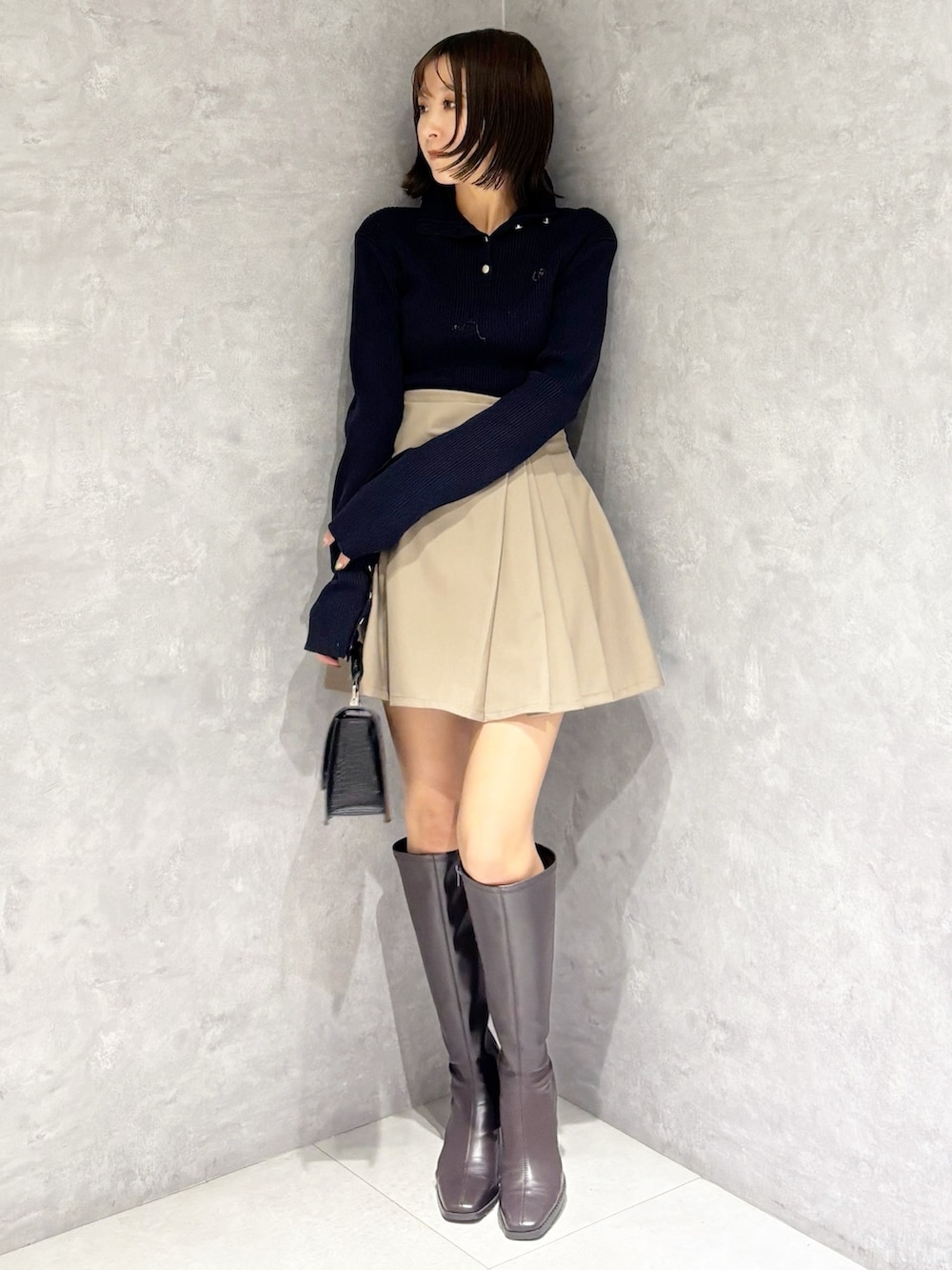 ベージュ系のスカート、ブラウン系のブーツ、ブラック系のハンドバッグを着用したレディースの冬コーディネートの5枚目の写真