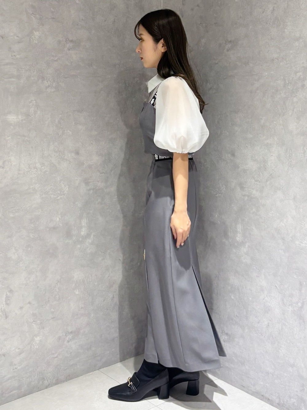 グレー系のスカート、ブラック系のブーツ、ホワイト系のハンドバッグを着用したレディースの春コーディネートの5枚目の写真