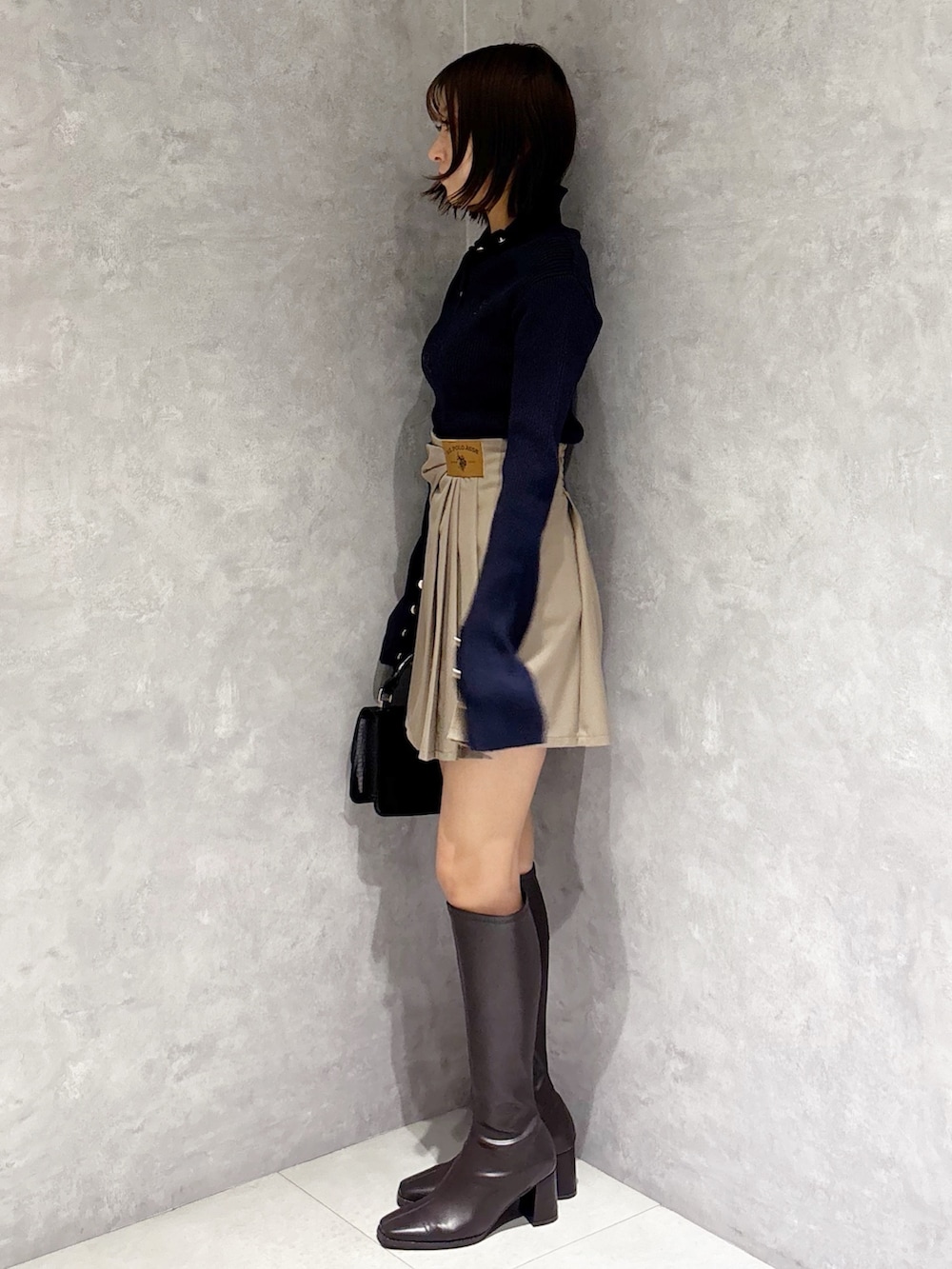 ベージュ系のスカート、ブラウン系のブーツ、ブラック系のハンドバッグを着用したレディースの冬コーディネートの4枚目の写真