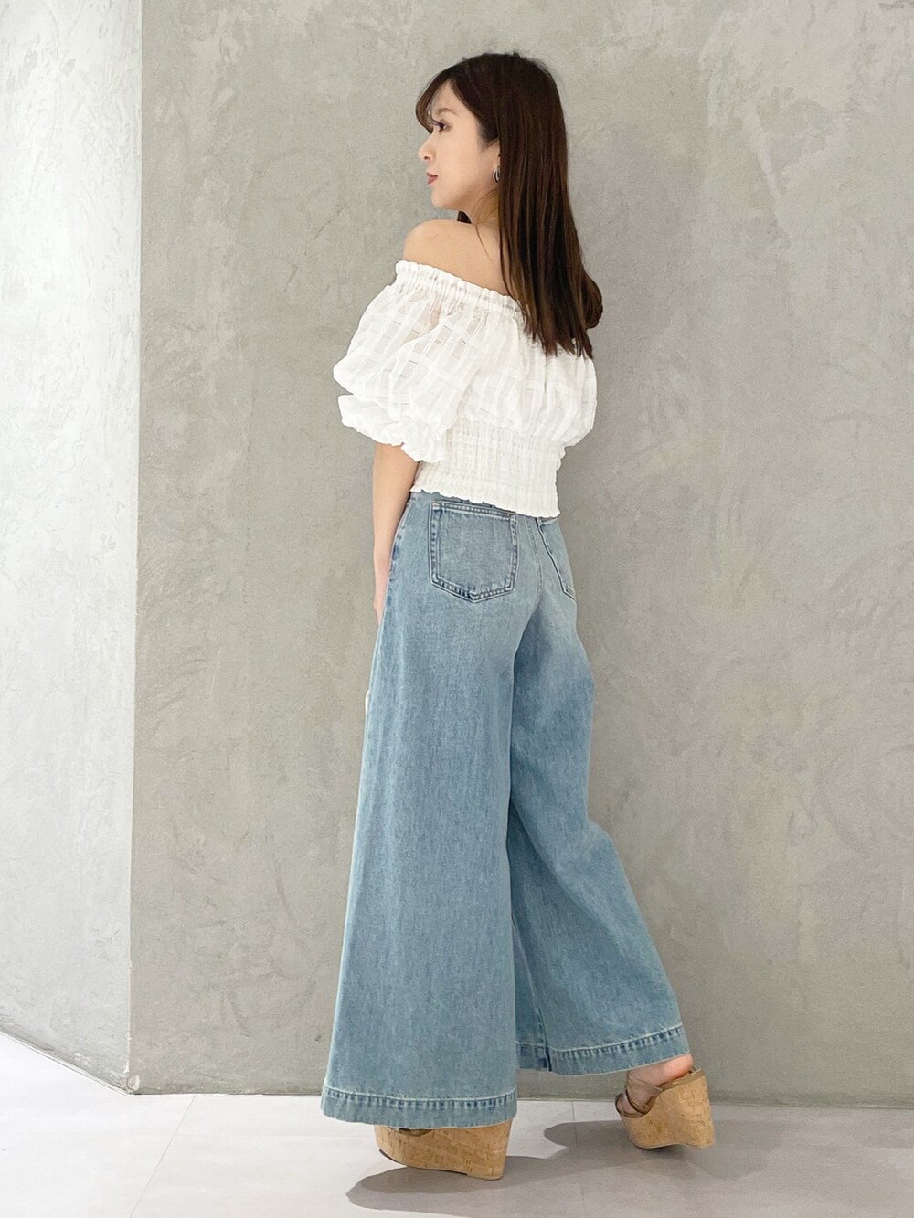 ブルー系のデニムパンツ、ブラウン系のサンダル、ホワイト系のハンドバッグを着用したレディースの春コーディネートの2枚目の写真