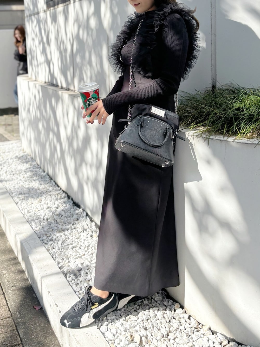 ブラック系のスカート、ブラック系のスニーカー、グレー系のニット/セーターを着用したレディースの秋コーディネートの5枚目の写真