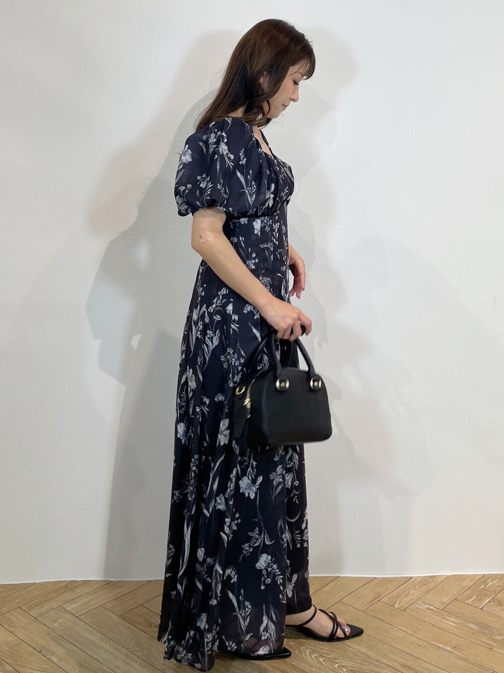 ブラック系のハンドバッグ、ブラック系のサンダル、グレー系のワンピースを着用したレディースの春コーディネートの3枚目の写真