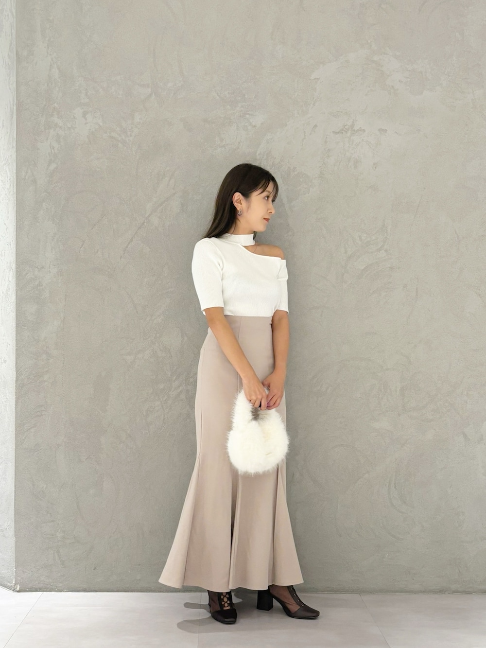 ピンク系のスカート、ブラウン系のブーツ、ホワイト系のハンドバッグを着用したレディースの秋コーディネートの5枚目の写真