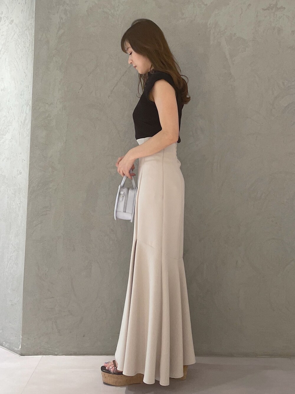 ブルー系のハンドバッグ、ブラック系のサンダル、ベージュ系のスカートを着用したレディースの春コーディネートの2枚目の写真