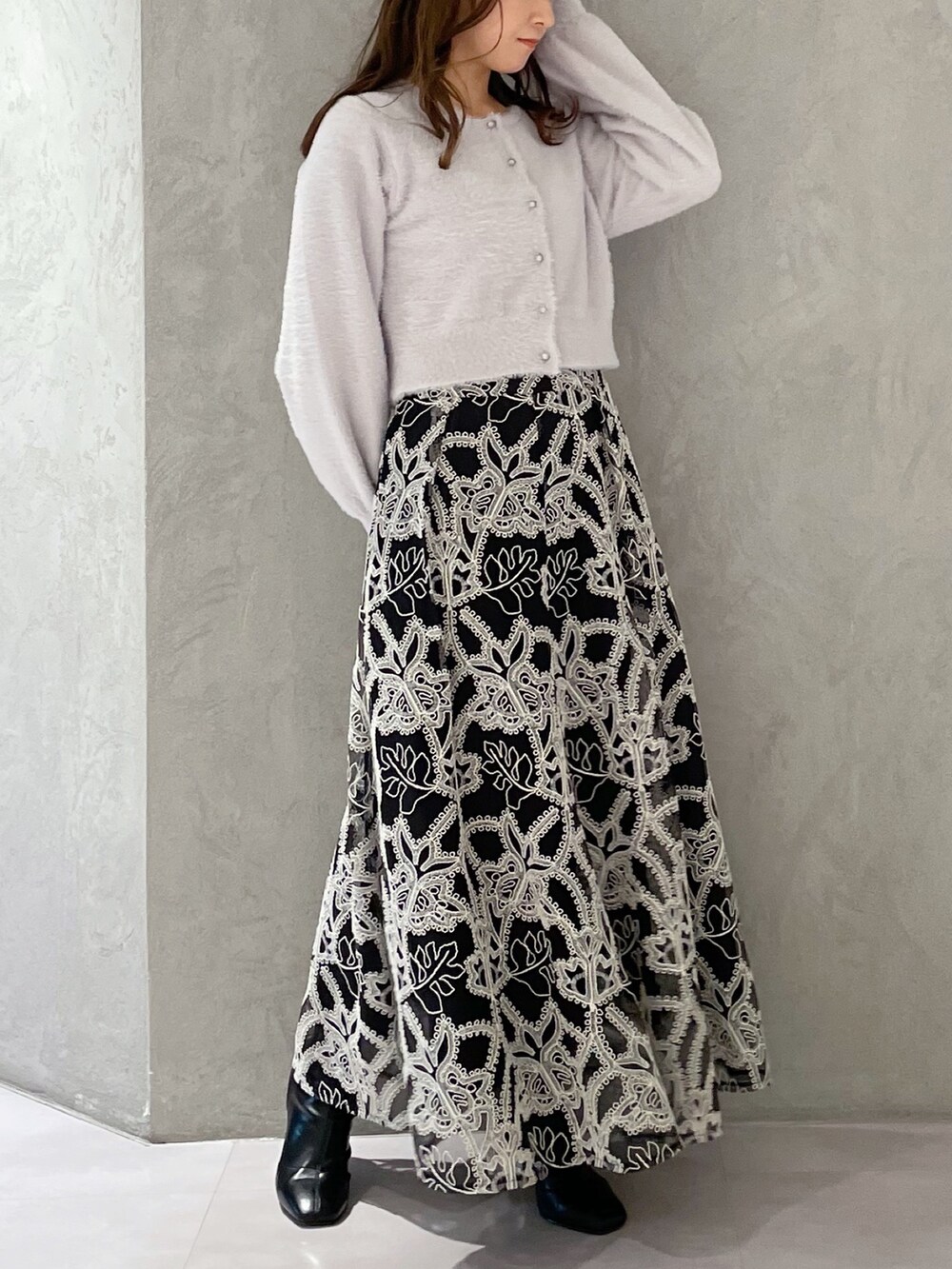 ブラック系のスカート、グレー系のカーディガン/ボレロ、ブラック系のブーツを着用したレディースの冬コーディネートの2枚目の写真