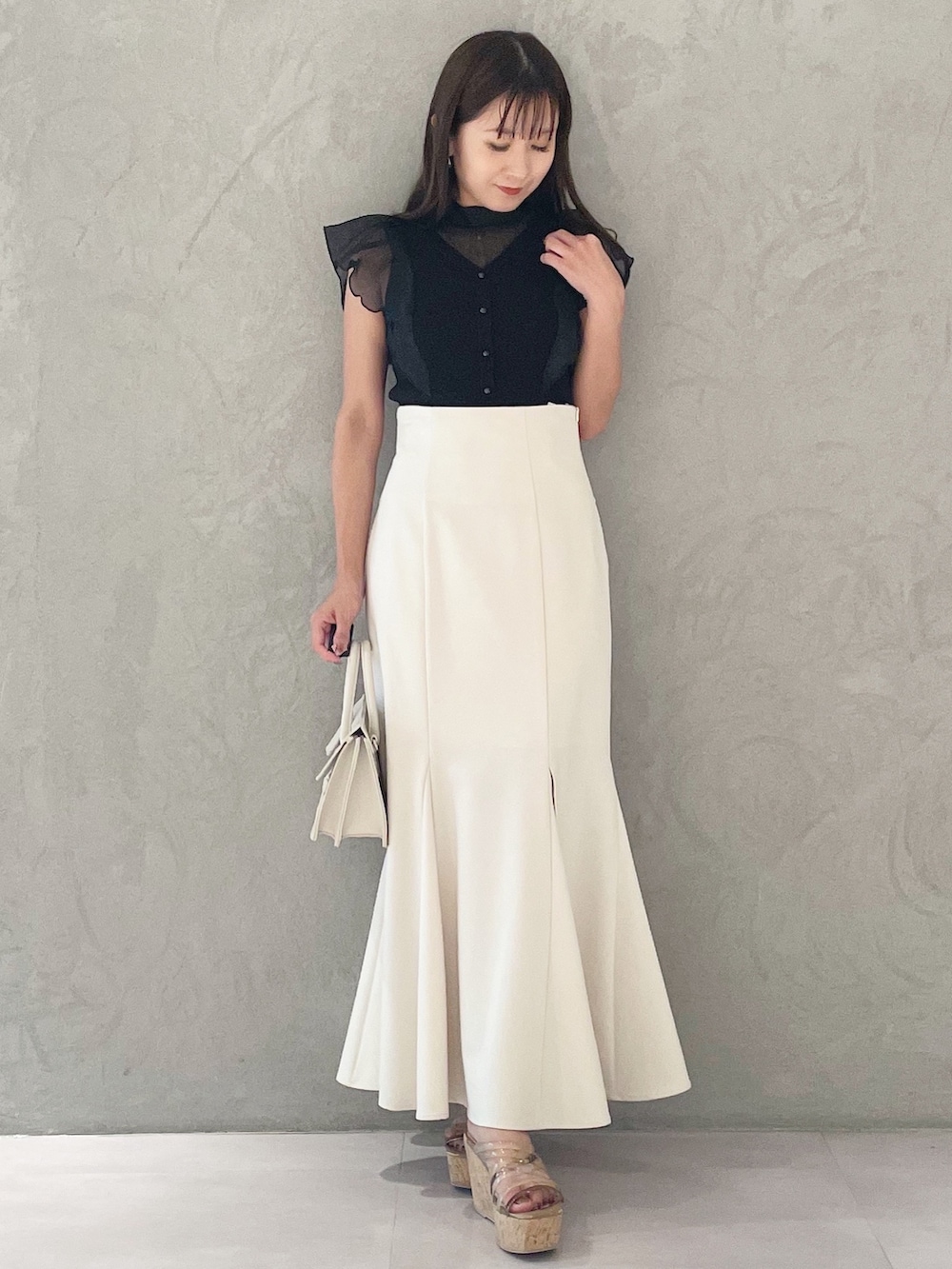 ブラック系のニット/セーター、ホワイト系のスカート、ブラウン系のサンダルを着用したレディースの夏コーディネートの3枚目の写真