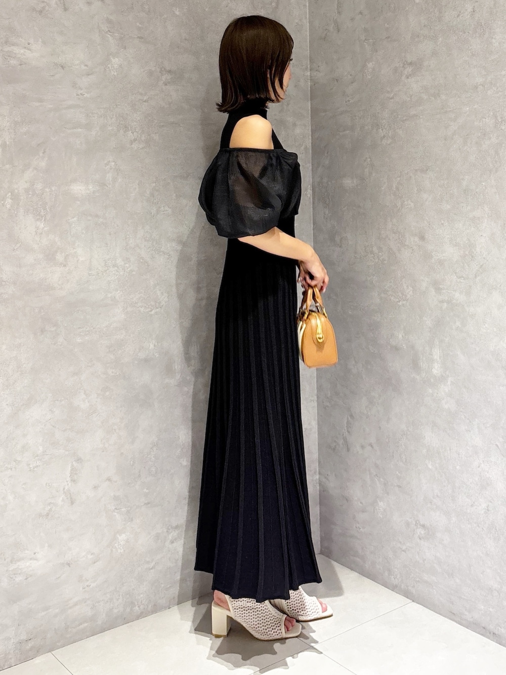 ブラウン系のハンドバッグ、ブラック系のワンピースを着用したレディースの春コーディネートの4枚目の写真