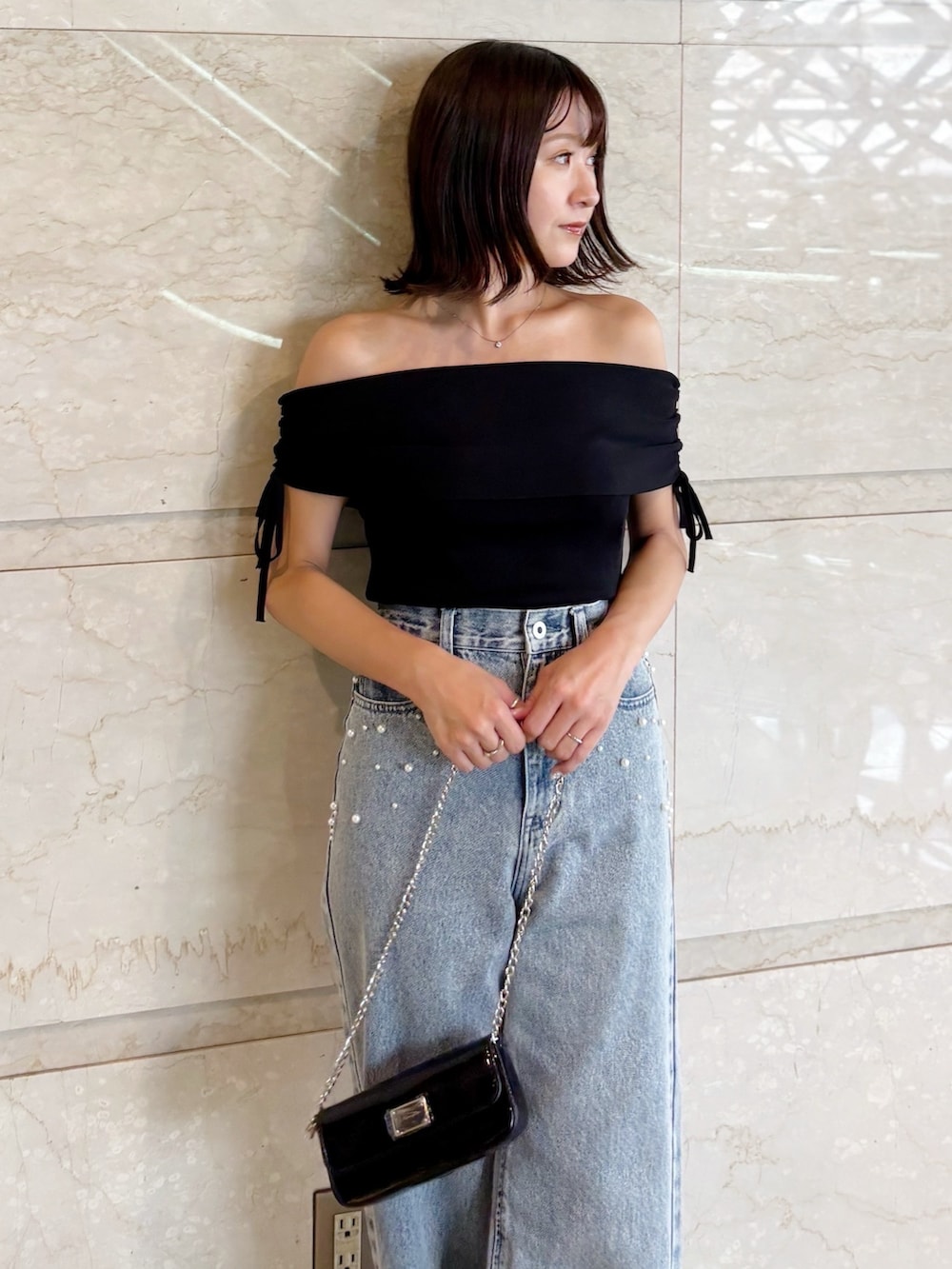 ブラック系のボディバッグ/ウエストポーチ、ブラック系のニット/セーター、ブルー系のデニムパンツを着用したレディースの夏コーディネートの4枚目の写真