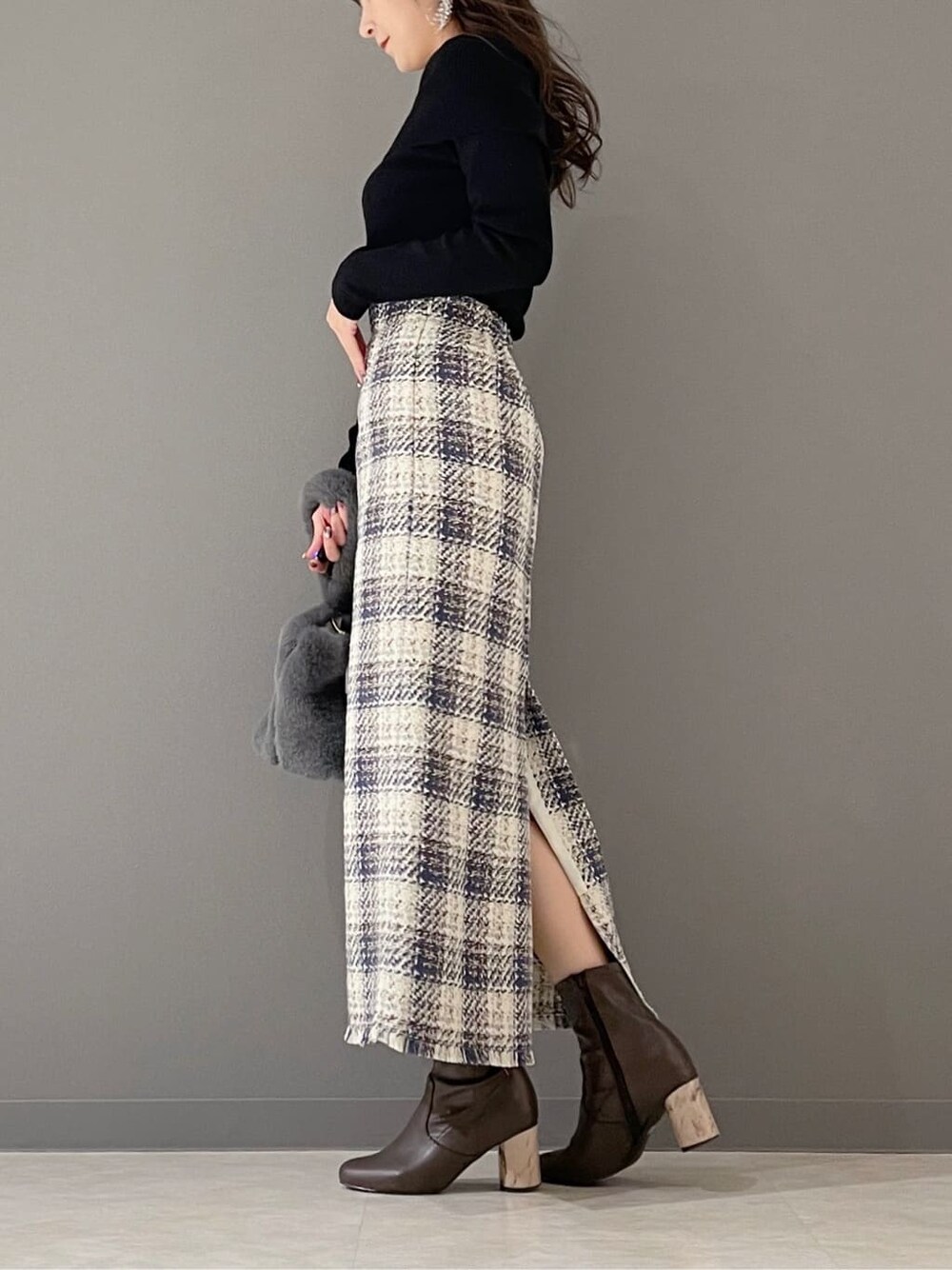 グリーン系のハンドバッグ、ブラック系のニット/セーター、ブルー系のスカートを着用したレディースの冬コーディネートの3枚目の写真