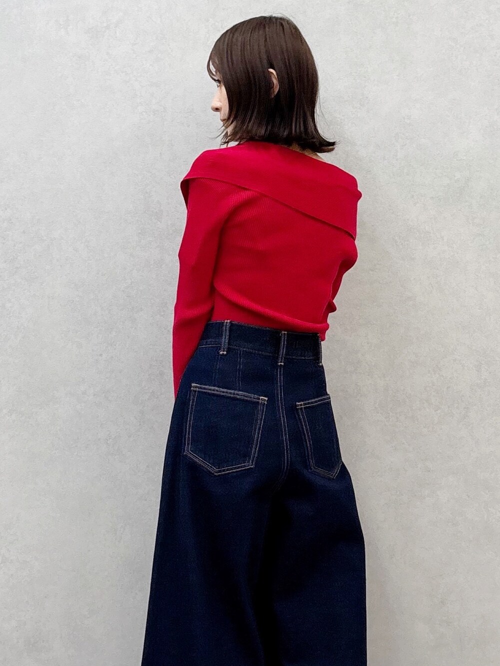 レッド系のニット/セーター、ブルー系のデニムパンツ、ブラウン系のブーツを着用したレディースの秋コーディネートの7枚目の写真