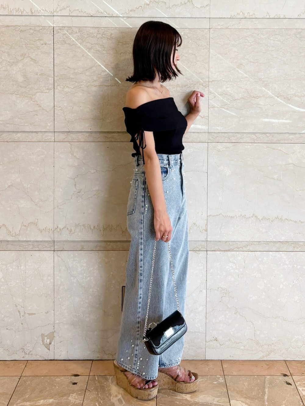 ブラック系のボディバッグ/ウエストポーチ、ブラック系のニット/セーター、ブルー系のデニムパンツを着用したレディースの夏コーディネートの2枚目の写真