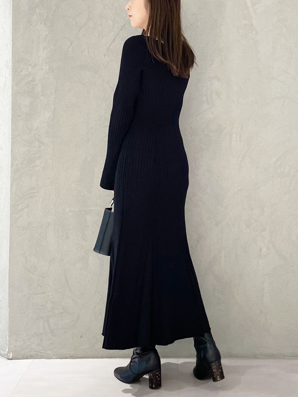 ブラック系のハンドバッグ、ブラック系のブーツ、ブラック系のワンピースを着用したレディースの冬コーディネートの3枚目の写真