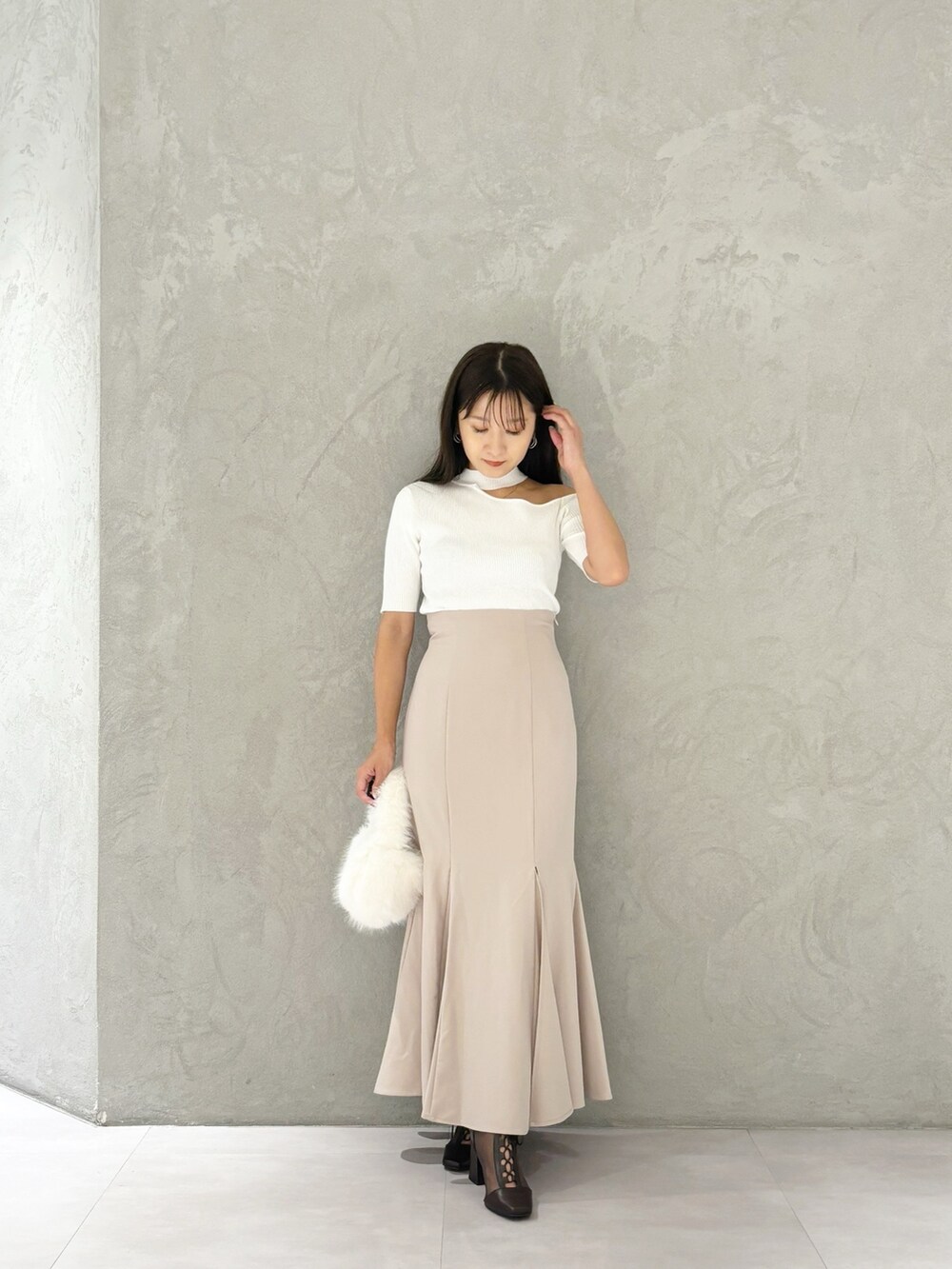 ピンク系のスカート、ブラウン系のブーツ、ホワイト系のハンドバッグを着用したレディースの秋コーディネートの6枚目の写真