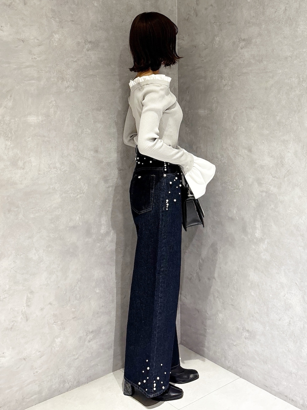 グレー系のニット/セーター、ブルー系のデニムパンツ、ブラック系のブーツを着用したレディースの秋コーディネートの4枚目の写真