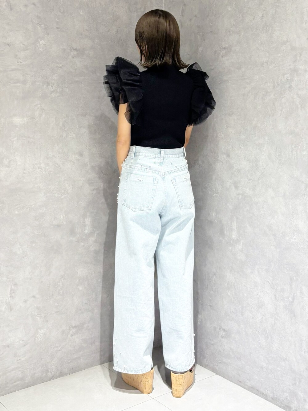 ブルー系のデニムパンツ、ブラック系のニット/セーター、ホワイト系のハンドバッグを着用したレディースの春コーディネートの4枚目の写真