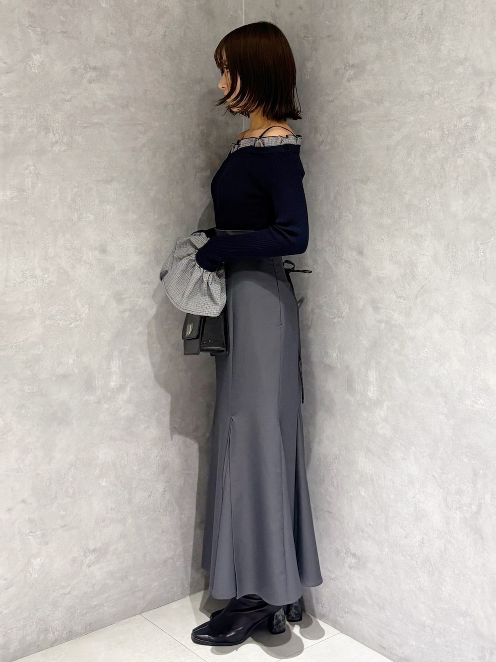 グレー系のスカート、ブラック系のハンドバッグ、ブルー系のニット/セーターを着用したレディースの冬コーディネートの5枚目の写真